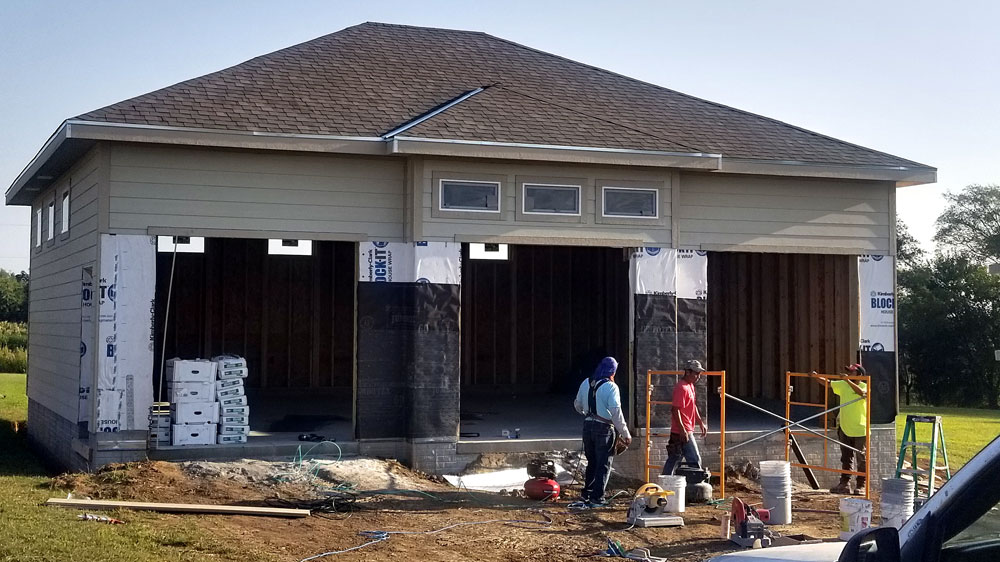 Three technicians working on the construction of a modern detached garage with three doors